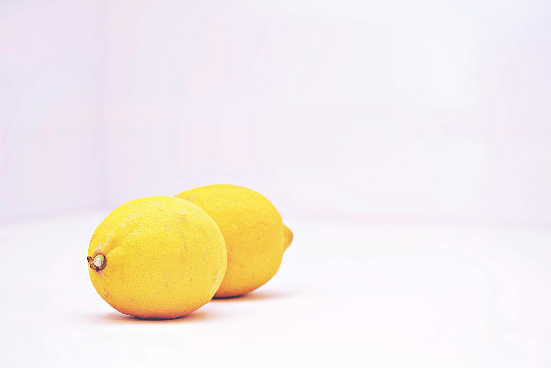 Two vibrant lemons on a minimalistic white background, symbolizing fresh approaches to pleasure and sensation.