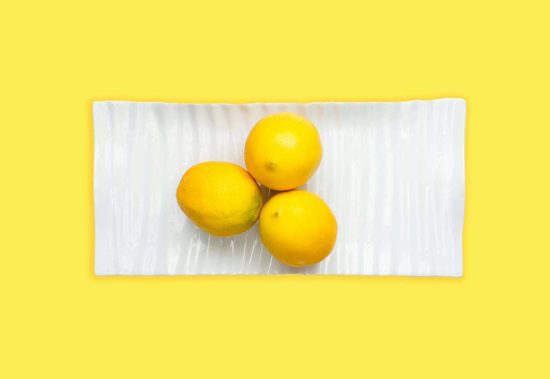 Fresh lemons on a white plate with yellow background, symbolizing a fresh start without pressure