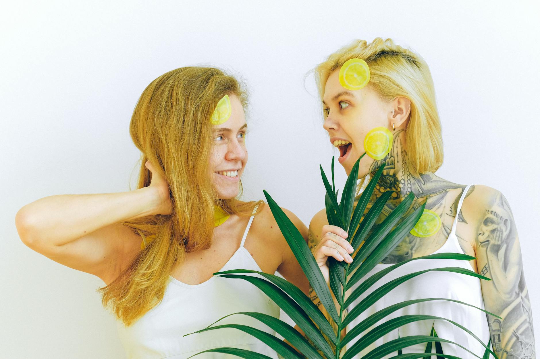 Two smiling women with lemon slices and tropical plant, expressing joy and safety during pregnancy