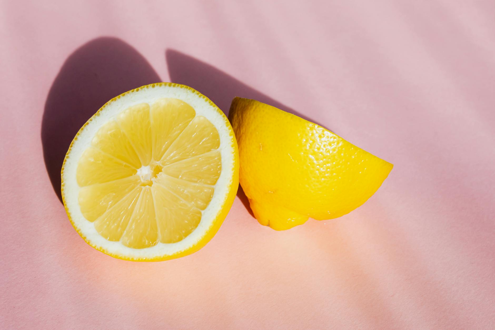 Fresh lemon halves on a pink background symbolizing the lemon clitoral vibrator