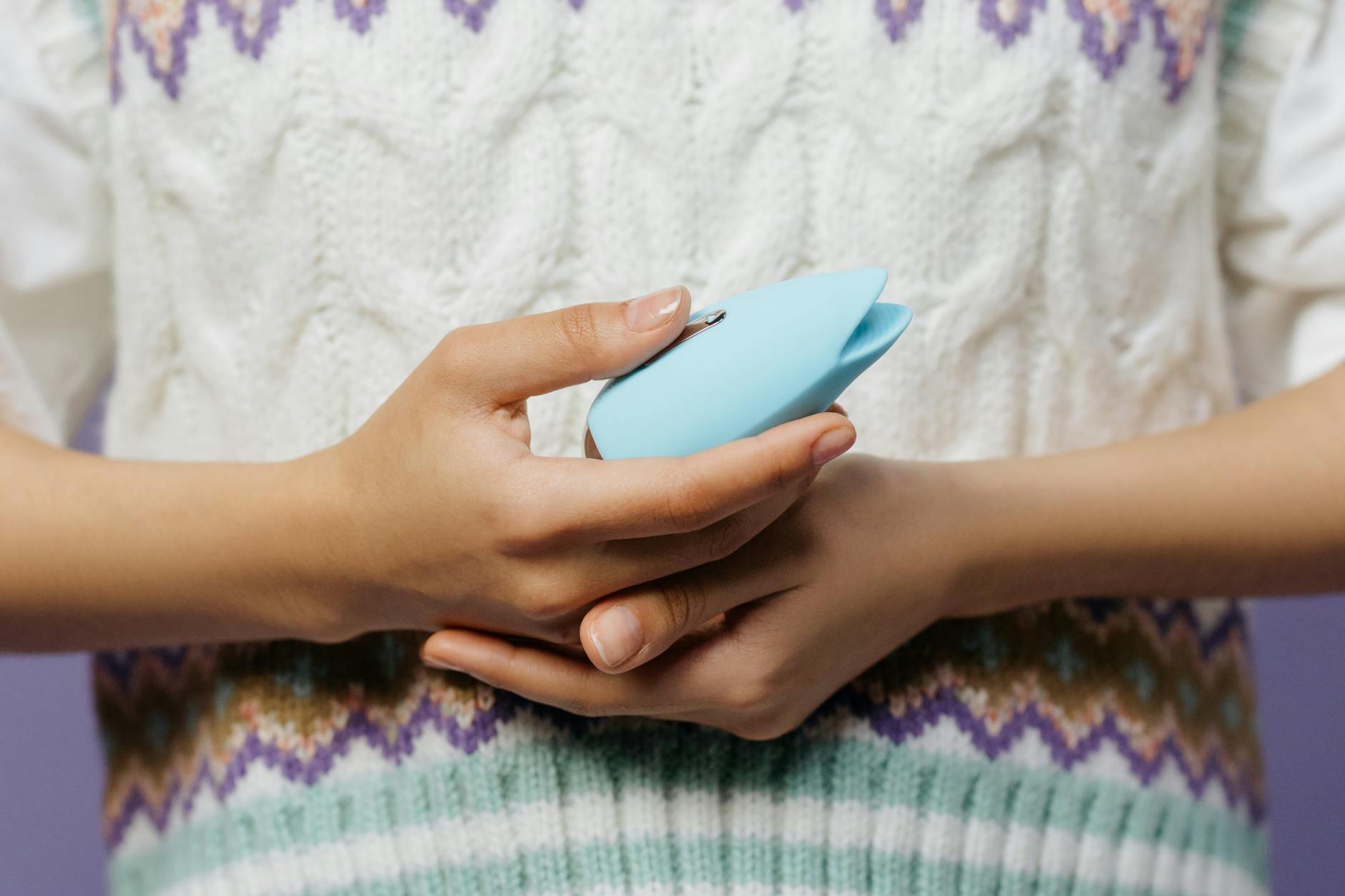 Person holding a blue lemon vibrator while sitting in comfortable clothing