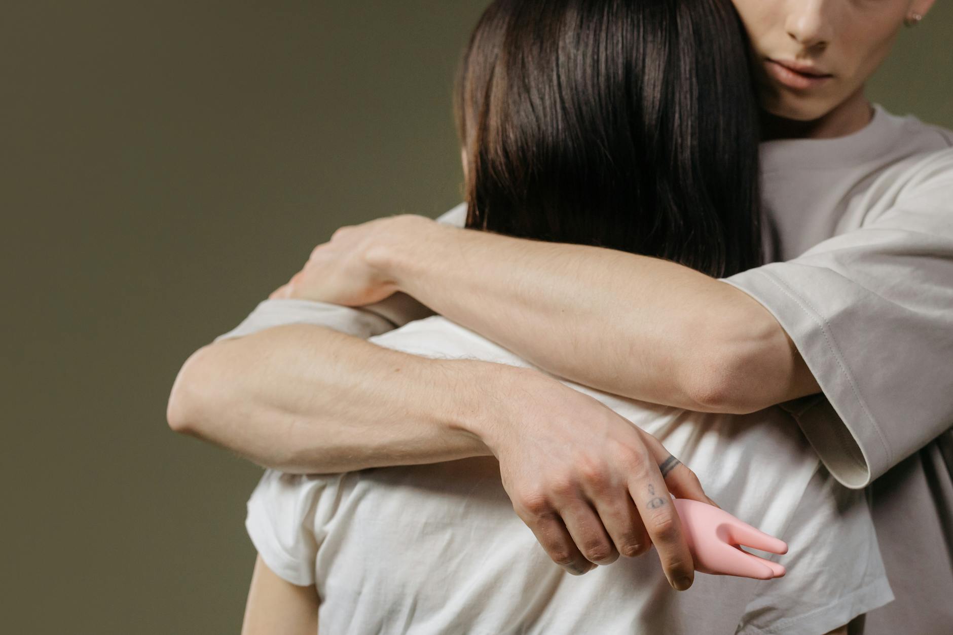 A young couple standing together indoors, holding a blue vibrator, symbolizing modern intimacy and open communication.