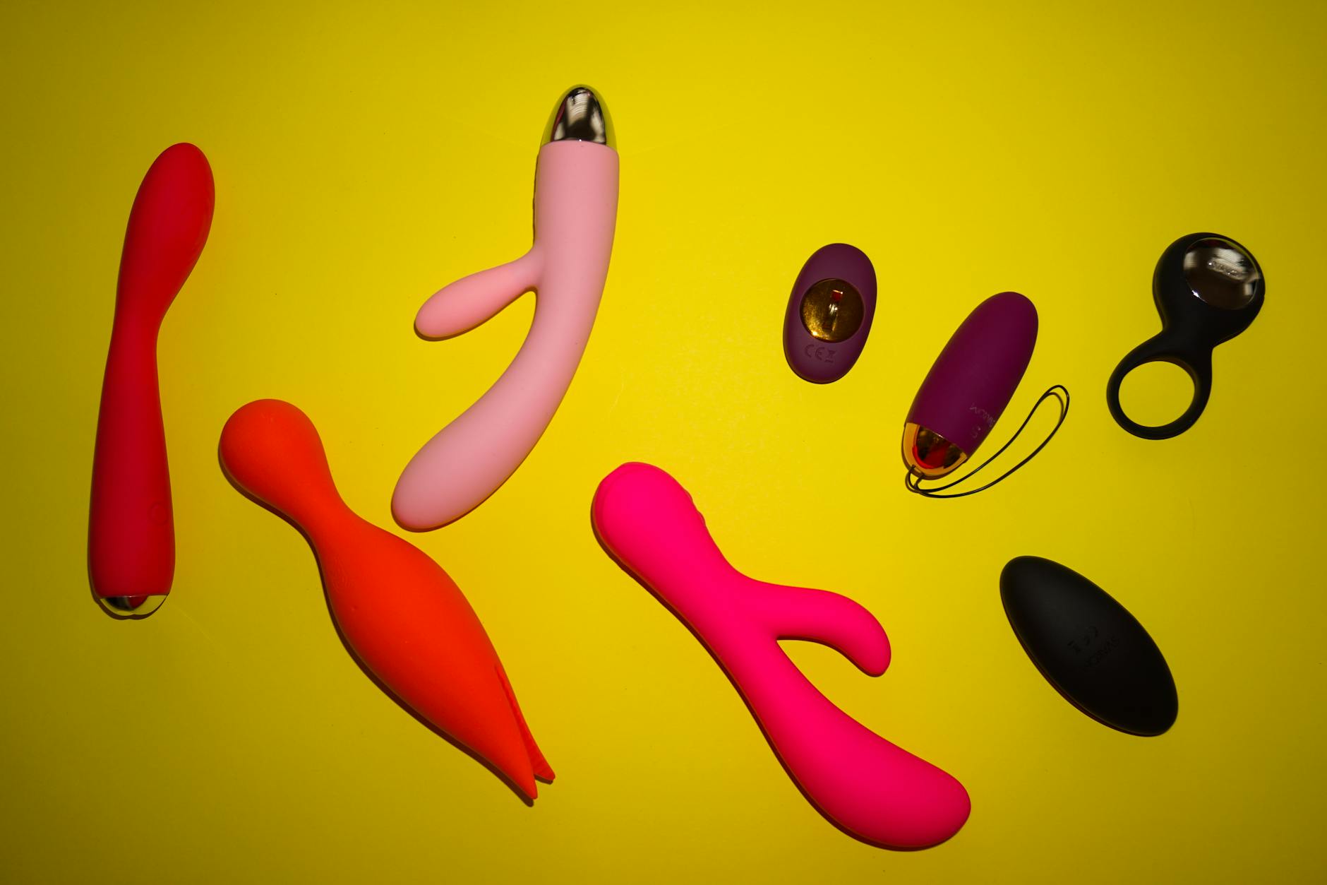Vibrant collection of colorful vibrators arranged on a bright yellow surface