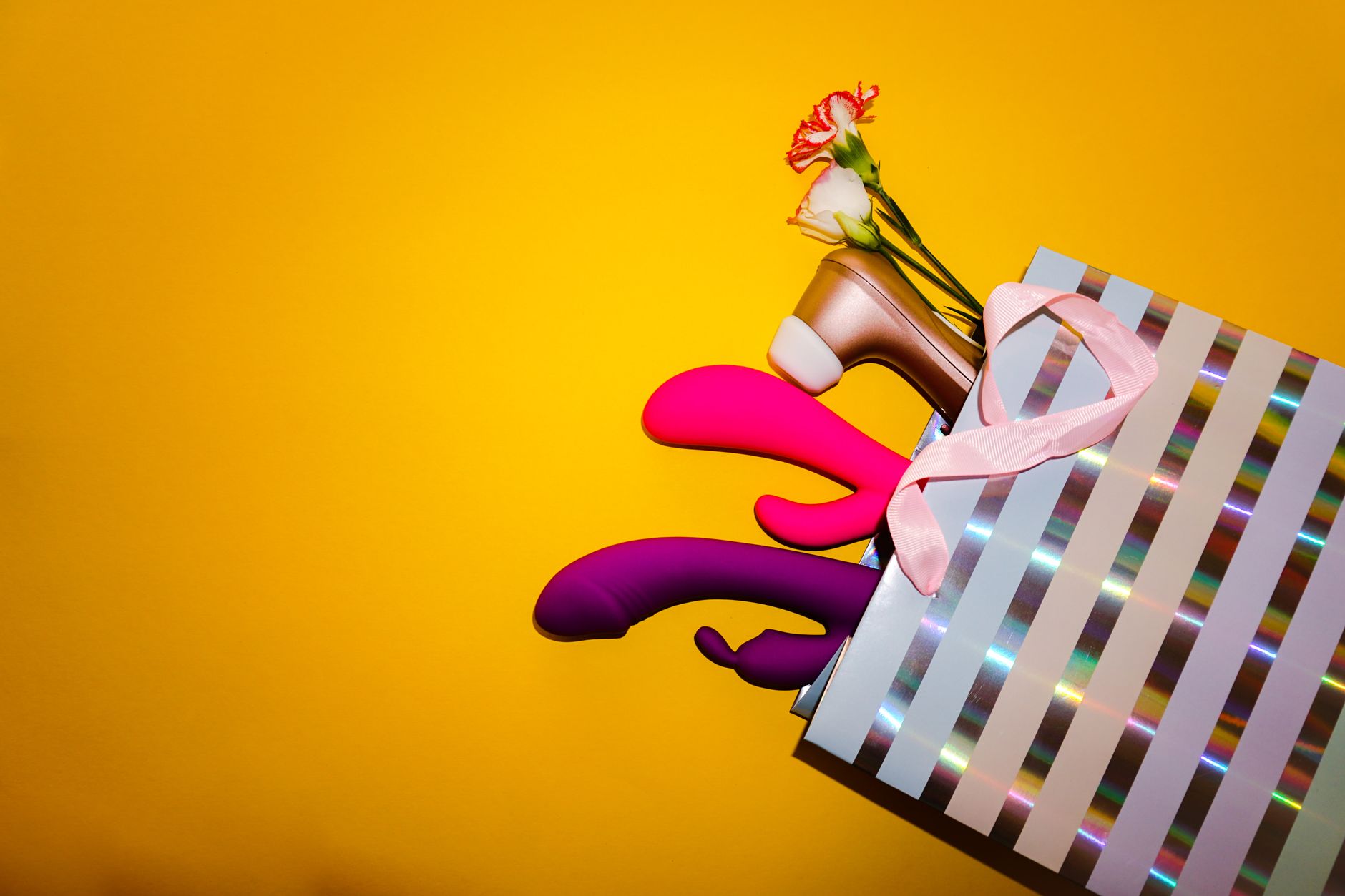 A hand with white nails holding a lemon on a soft pink background