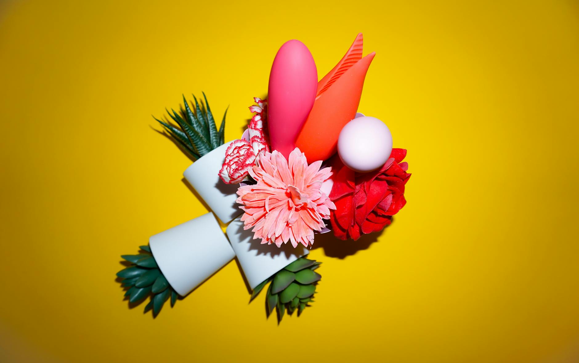 Studio setup showcasing colorful sex toys on a bright yellow background, featuring various shapes and designs